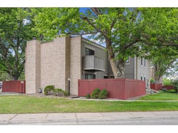 Two-story townhouse featuring brick accents, a balcony, and a cozy front courtyard with mature trees at 1254 S Yosemite Way # 99, Denver, CO 80247