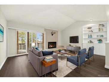 Bright living room with vaulted ceilings, fireplace, and sliding doors to the outside, creating an airy and inviting space at 6300 W Mansfield Ave # 61, Denver, CO 80235