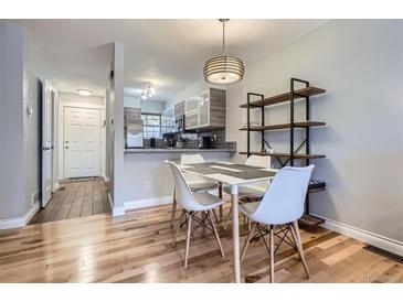 Bright dining area featuring wood floors, pendant lighting, and open access to the kitchen at 1818 S Quebec Way # 11-8, Denver, CO 80231