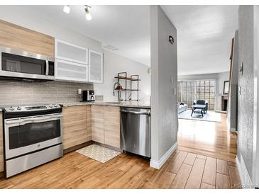 Modern kitchen with stainless steel appliances, stylish cabinets, and sleek countertops, seamlessly flowing into the living area at 1818 S Quebec Way # 11-8, Denver, CO 80231