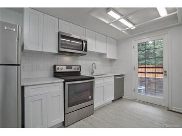 Modern kitchen features white cabinets, stainless steel appliances, and backsplash at 4134 S Fraser Way # E, Aurora, CO 80014