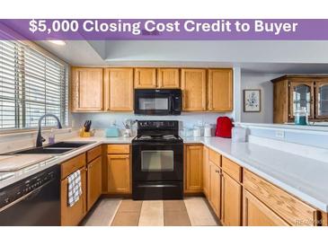 Well-lit kitchen features a black microwave and oven, light wood cabinets, and lots of counter space at 8199 Welby Rd # 3102, Denver, CO 80229