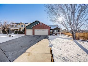 Brick home with three-car garage and snowy front yard at 10976 W 55Th Ln, Arvada, CO 80002