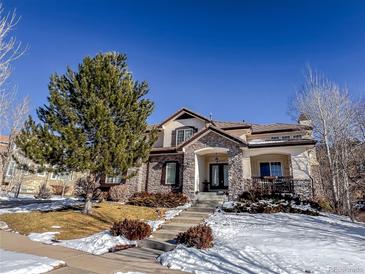 Two-story house with stone accents, a covered entry, and a landscaped yard with snow at 24237 E Glasgow Cir, Aurora, CO 80016