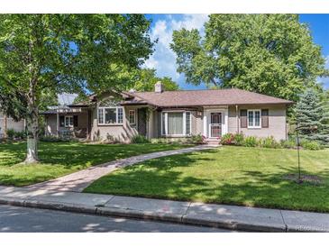 Charming single-story brick home with lush green lawn, mature trees, and inviting walkway at 801 S Steele St, Denver, CO 80209