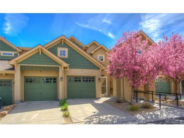 Inviting exterior showcasing a charming townhome with attached garage and a lovely blooming tree in the front yard at 11932 W Long Cir # 202, Littleton, CO 80127