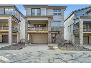 Modern two-story townhome with a gray exterior, a balcony, a two-car garage, and brick accents at 3172 S Russell St, Morrison, CO 80465