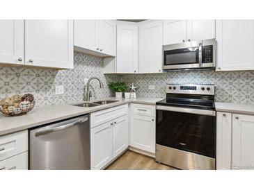 Bright kitchen featuring stainless steel appliances, sleek countertops, stylish backsplash, and white cabinetry at 765 S Alton Way # 4A, Denver, CO 80247