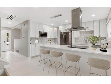 Bright, modern kitchen with white cabinets, stainless steel appliances, and a spacious island at 12992 W Jewell Cir, Lakewood, CO 80228