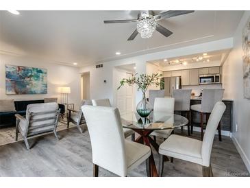 A modern living room featuring a glass table, stylish chairs, and an open-concept kitchen at 14150 E Temple Dr # V06, Aurora, CO 80015