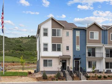 Inviting exterior of a multi-level townhouse with white and brown siding plus landscaped front at 14492 Pansy Loop, Morrison, CO 80465