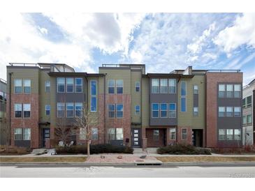 A modern townhouse exterior with brick and siding details, set against a cloudy sky at 8722 E 47Th Ave, Denver, CO 80238