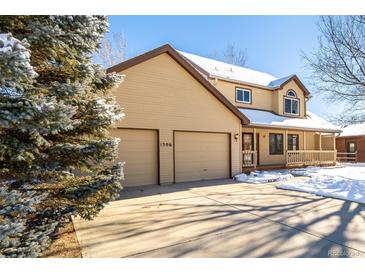 Two-story house with beige siding, attached two-car garage, and a covered porch at 1506 Maple Dr, Berthoud, CO 80513