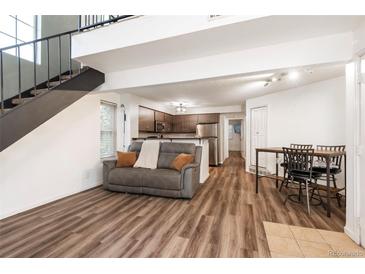 Open living space with wood floors, staircase, and view of kitchen and dining area at 13744 E Lehigh Ave # B, Aurora, CO 80014