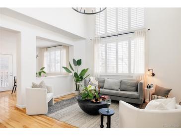 Bright living room features hardwood floors, a cozy seating area, and large windows at 10283 Spotted Owl Ave, Highlands Ranch, CO 80129