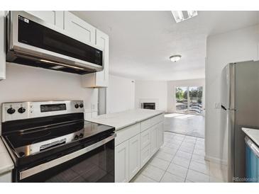 Bright kitchen boasts stainless appliances, white cabinetry, and a center island open to the living area at 13095 W Cedar Dr # 302, Lakewood, CO 80228