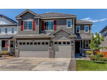 Beautiful two-story home with a three-car garage, stone accents, and a well-maintained front lawn at 14763 Pepper Pike Pl, Parker, CO 80134