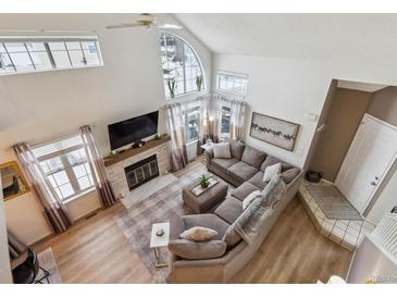 High-ceilinged living room with a fireplace and large windows at 5885 W Atlantic Pl, Lakewood, CO 80227