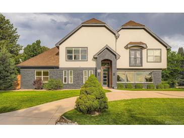 Charming two-story home boasts a unique facade, a manicured lawn, and beautiful landscaping at 22 Rangeview Dr, Wheat Ridge, CO 80215