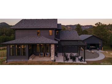 Stunning two-story home with a dark wood exterior and stone accents, plus a backyard patio with mountain views at 30796 Burland Rd, Golden, CO 80403