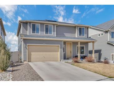 Two-story gray home with a beige two car garage and an easy to maintain lawn on a bright sunny day at 5251 Truckee St, Denver, CO 80249