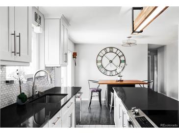 Bright kitchen features white cabinetry, stylish backsplash, and black countertops, creating a modern and inviting space at 11354 Allendale Dr, Arvada, CO 80004