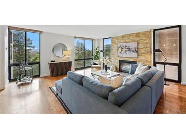 Bright living room features a stone fireplace, hardwood floors, and large windows with scenic outdoor views at 1111 Race St # 6B, Denver, CO 80206