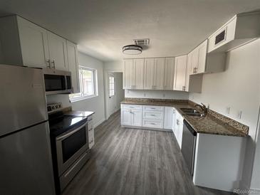 Bright kitchen features stainless appliances, granite counters, white cabinets, and wood flooring at 1550 Eppinger Blvd, Thornton, CO 80229