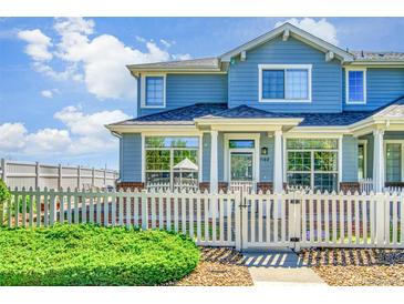 Charming blue townhome with white picket fence, lush green bush, and well-maintained landscaping at 9102 W 107Th Pl, Broomfield, CO 80021