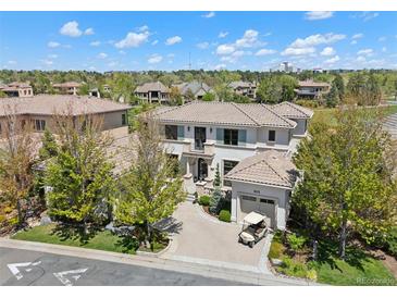 Elegant two-story home with a tile roof, lush landscaping, and a golf cart parked on the driveway at 9171 E Harvard Ave, Denver, CO 80231