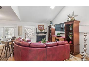 Comfortable living room with vaulted ceilings, fireplace, large sectional sofa, and hardwood floors at 2752 S Heather Gardens Way, Aurora, CO 80014