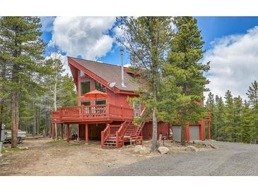 Red cabin home with a large deck nestled among the trees in a mountain setting at 387 Pine Dr, Idaho Springs, CO 80452