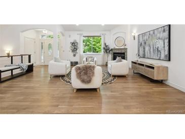 Bright living room with fireplace, modern art, and large window letting in natural light at 1235 S Balsam St, Lakewood, CO 80232