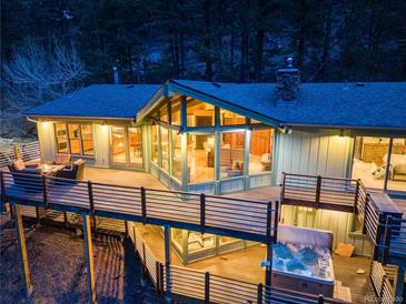 Stunning exterior view showcasing a spacious deck, hot tub, and ample windows offering beautiful views of the surrounding landscape at 994 Timber Ln, Boulder, CO 80304