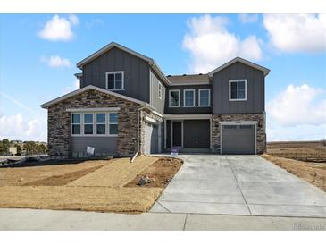 A charming new two-story home featuring stone accents, gray siding, a driveway, and a manicured lawn at 13710 Emerald Lake St, Parker, CO 80138