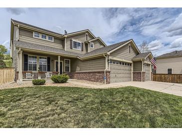 Charming two-story home featuring a covered front porch, three-car garage, and manicured lawn at 11895 Hitching Post Ct, Parker, CO 80134