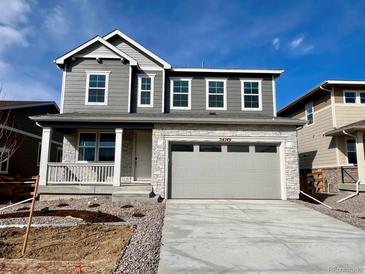 Charming two-story home featuring a stone facade, gray siding, a two-car garage, and a welcoming front porch at 24749 E 39Th Ave, Aurora, CO 80019