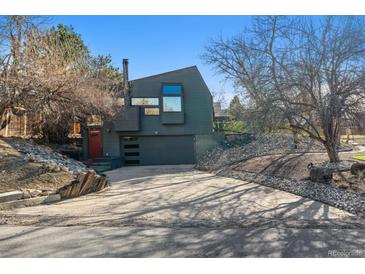 Modern two-story home with a red door, a garage, and unique window placements at 7770 S Estes St, Littleton, CO 80128
