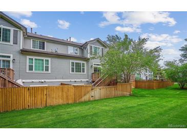 A spacious backyard with lush green grass, a wooden fence, and a patio area perfect for outdoor entertaining at 1441 S Ulster St, Denver, CO 80231