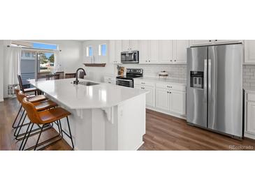 Bright kitchen with white cabinetry, stainless steel appliances, and an expansive center island at 10200 Xanadu St, Commerce City, CO 80022