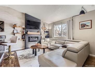 Comfortable living room featuring a modern fireplace, flat screen TV, and light gray leather sectional sofa at 4063 S Quintero Way, Aurora, CO 80013