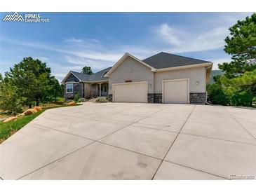 Charming single-story home featuring a three-car garage and a wide driveway on a sunny day at 18376 Heavens Pl, Monument, CO 80132
