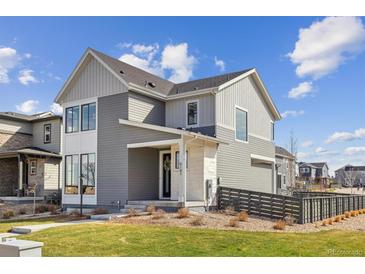 Modern two-story home featuring gray siding, a covered porch, and well-kept landscaping at 6181 Saddlesmith St, Castle Pines, CO 80108