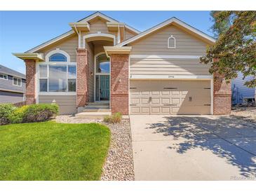 Charming home features a well-manicured lawn, brick accents, and an attached two-car garage at 22436 E Maplewood Pl, Aurora, CO 80015