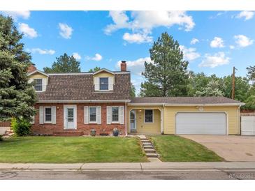 Charming two-story home featuring a brick facade, well-manicured lawn, mature trees, and an attached two car garage at 1487 W Fair Ave, Littleton, CO 80120