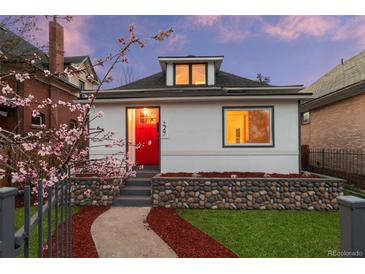 Charming home featuring a red front door, river rock landscaping, and blooming tree at 2767 W 38Th Ave, Denver, CO 80211