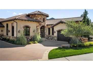 Stunning home featuring a stone turret, tile roof, and lush landscaping at 7188 Raphael Ln, Littleton, CO 80125