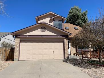 Tan two-story home featuring an attached two-car garage, brick accents, and a well-manicured front yard at 11375 W Maplewood Ave, Littleton, CO 80127