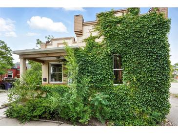 Two-story house with brick and tan trim covered in a lush green vine facade at 416 W 3Rd Ave, Denver, CO 80223