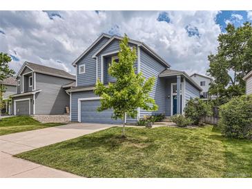 Two-story home with blue siding, well-manicured lawn, and attached garage showcases great curb appeal at 8750 Redwing Ave, Littleton, CO 80126